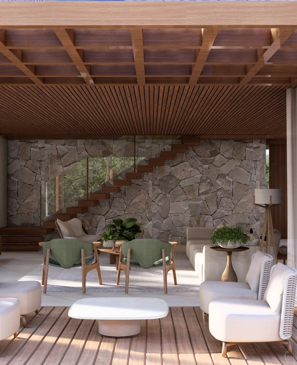 Living area opening onto the deck, with a natural stone wall, light armchairs and a timber staircase